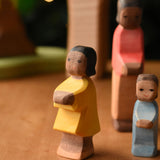 Ostheimer daughter with brown skin wooden toy figure placed at the front of a small world play scene. These wooden figures are part of a wide range of expertly hand crafted wooden toys here at Babipur.