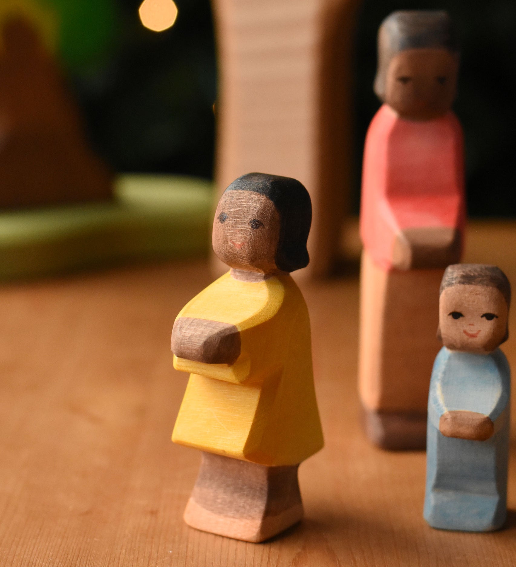 Ostheimer daughter with brown skin wooden toy figure placed at the front of a small world play scene. These wooden figures are part of a wide range of expertly hand crafted wooden toys here at Babipur.
