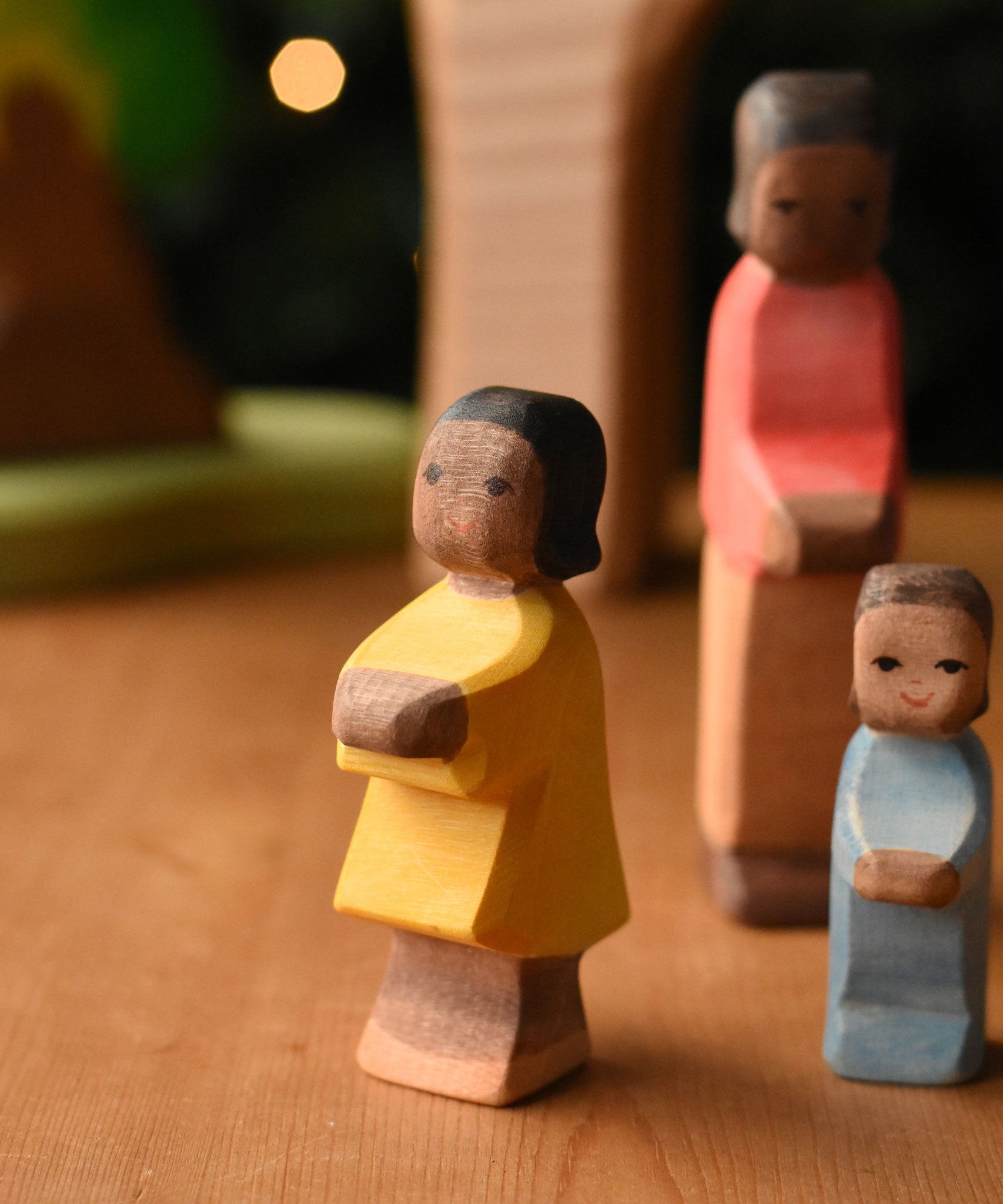 Ostheimer daughter with brown skin wooden toy figure placed at the front of a small world play scene. These wooden figures are part of a wide range of expertly hand crafted wooden toys here at Babipur.