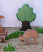 An Ostheimer eating deer wooden toy figure placed in a small world play scene with other fawn and deer and Ostheimer grass and an oak tree. Check out our full range of expertly crafted wooden toy figures and scenery here at Babipur.
