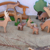 A collection of Ostheimer deer and fawn wooden figures placed in a small world play scene set up with a wooden toy bridge, oak tree and green grass figures. Check out our full range of expertly crafted wooden toy figures and scenery here at Babipur.