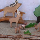 A collection of Ostheimer deer and fawn shown in a small world play scene with a wooden toy bridge and trees and branches. Check out our full range of expertly crafted wooden toy figures and scenery here at Babipur.