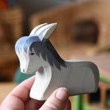 Ostheimer donkey laying down wooden toy figure in an adult's hands. 