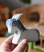 Ostheimer donkey laying down wooden toy figure in an adult's hands. 