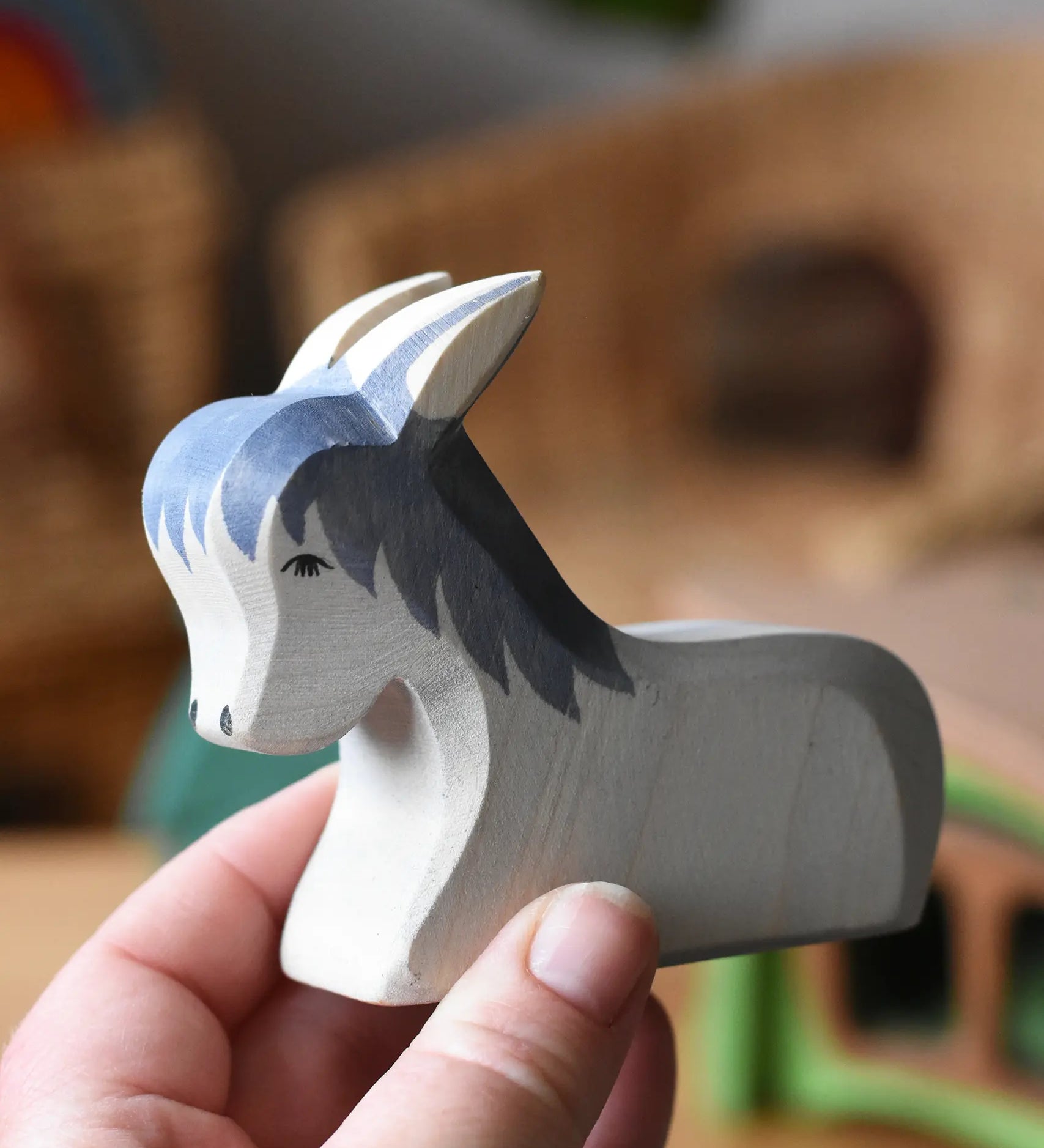 Ostheimer donkey laying down wooden toy figure in an adult's hands. 