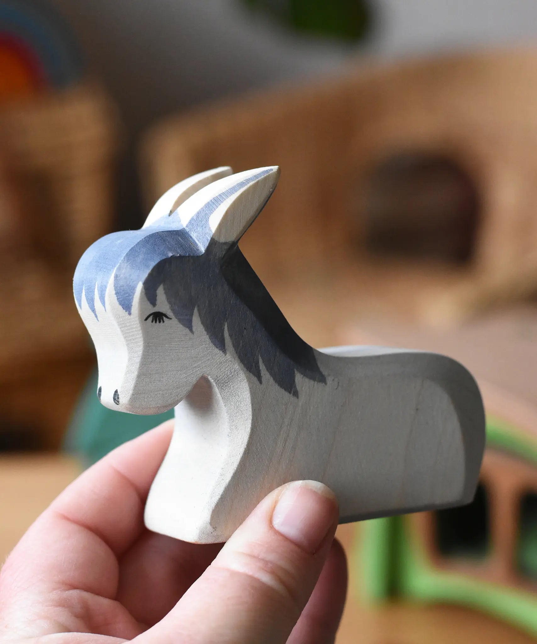 Ostheimer donkey laying down wooden toy figure in an adult's hands. 