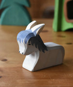 Ostheimer donkey laying down wooden toy figure placed on a wooden surface.