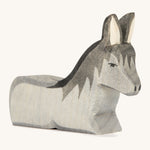 A grey wooden lying donkey on a cream background