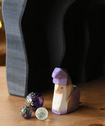 Ostheimer amethyst purple wooden dwarf figure placed underneath the dragon's cave arches next to three Billes glass marbles. 