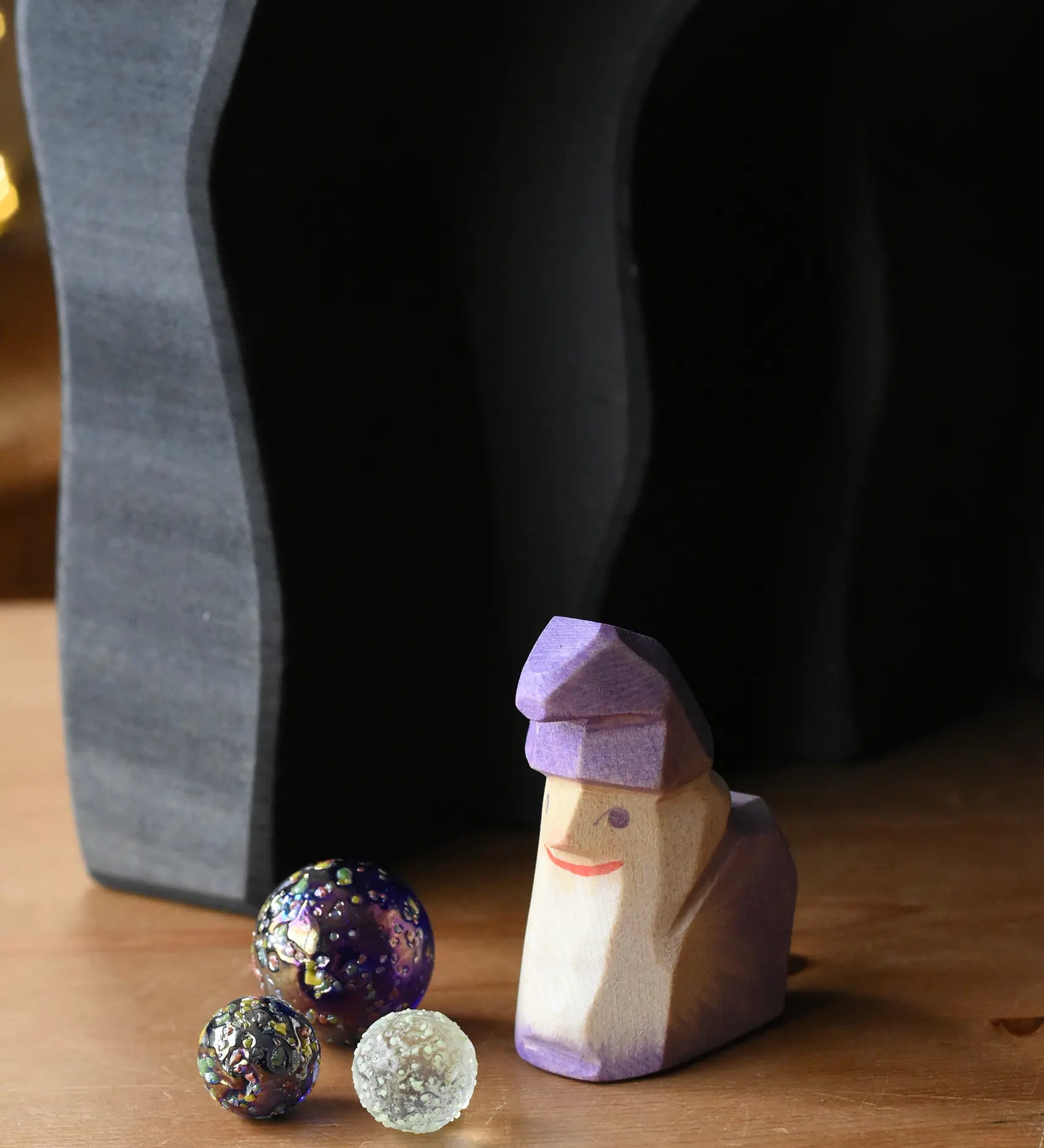 Ostheimer amethyst purple wooden dwarf figure placed underneath the dragon's cave arches next to three Billes glass marbles. 