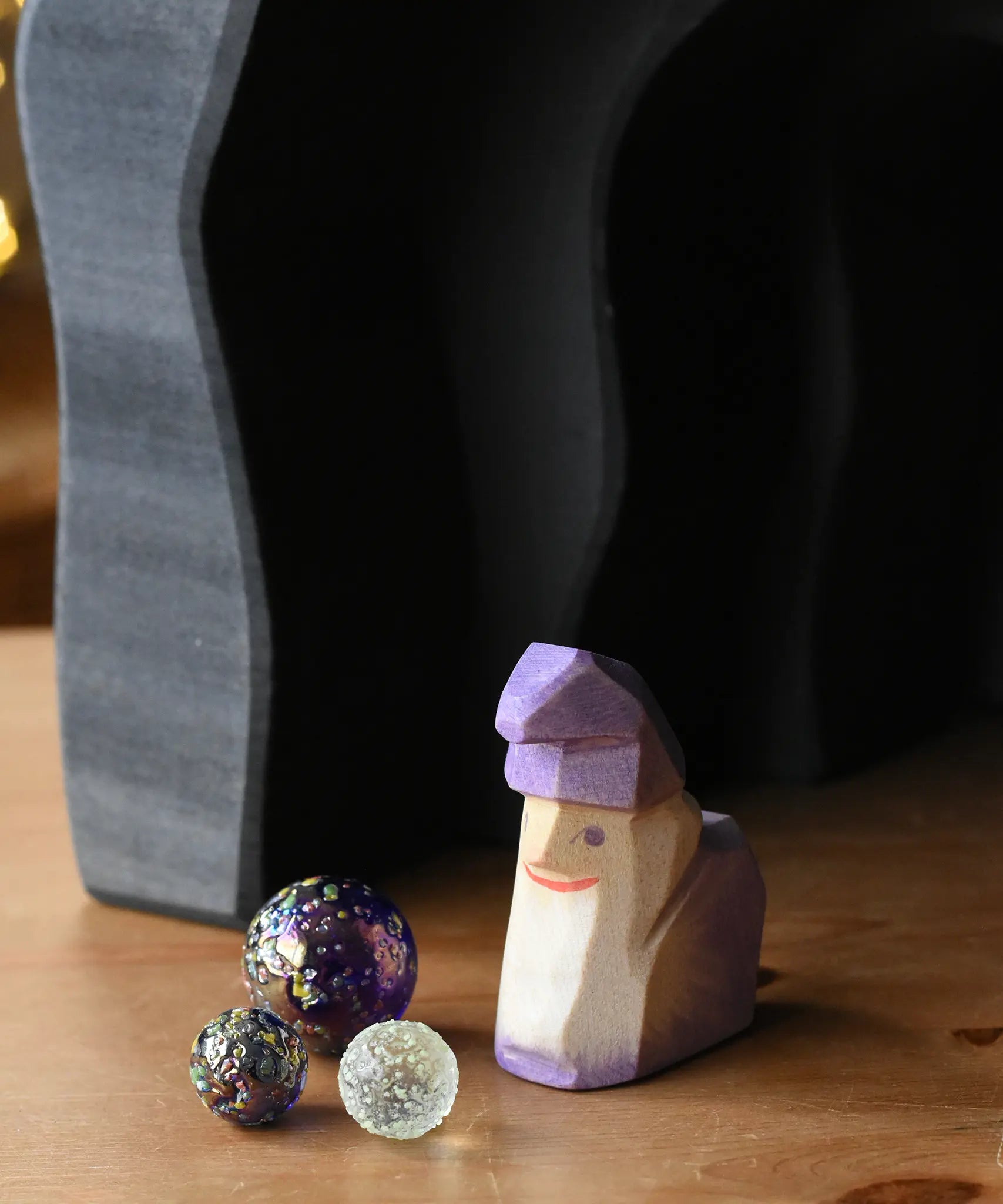 Ostheimer amethyst purple wooden dwarf figure placed underneath the dragon's cave arches next to three Billes glass marbles. 