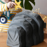 Back of the black Ostheimer dragon's cave, a child is placing a yellow wooden star decoration on top.