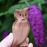 An Ostheimer brown coloured eagle owl shown in an adult's hand for scale. The owl figure is part of a large collection of expertly hand crafted wooden toys and figures here at Babipur. 