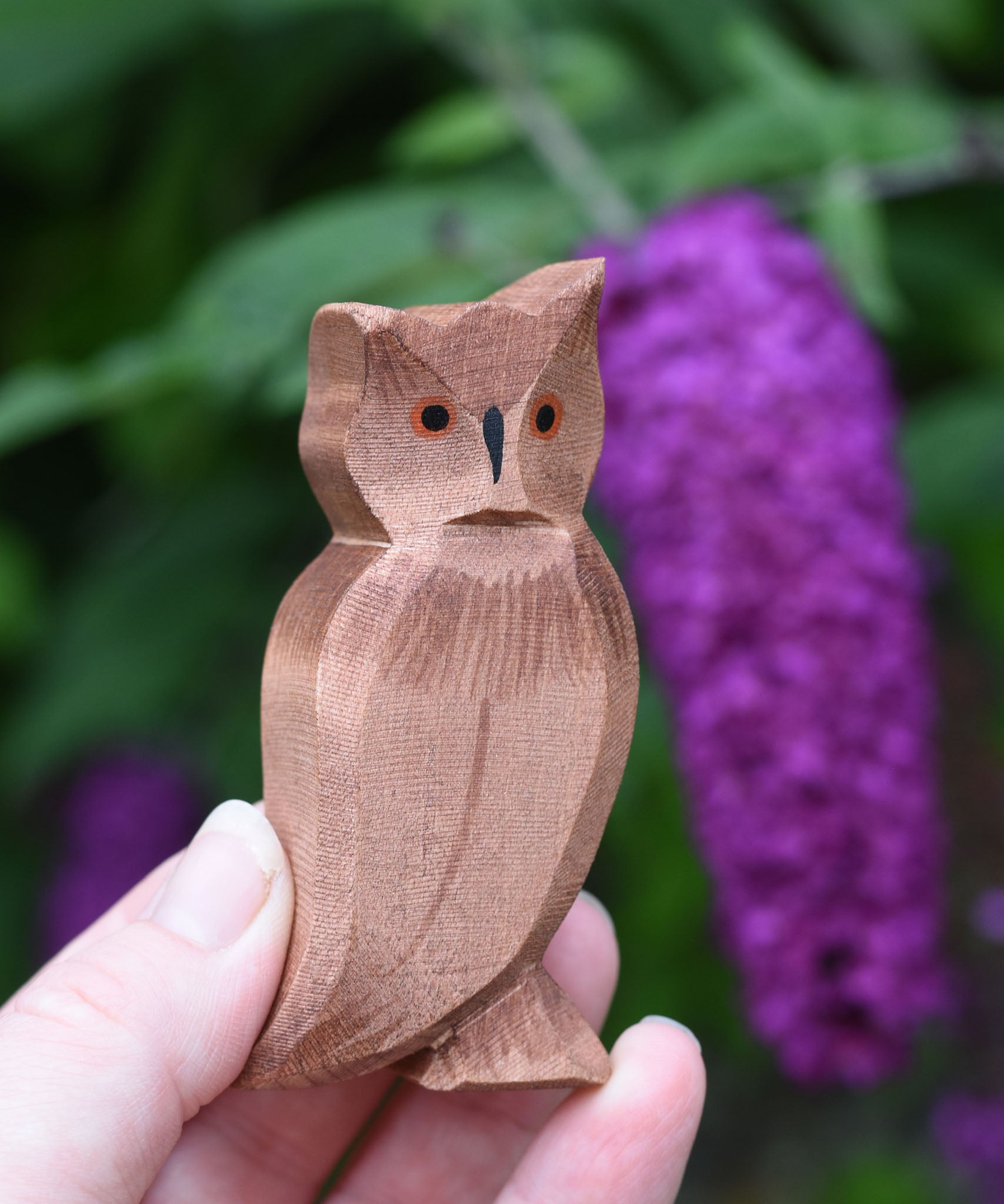 An Ostheimer brown coloured eagle owl shown in an adult's hand for scale. The owl figure is part of a large collection of expertly hand crafted wooden toys and figures here at Babipur. 