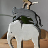 Stack of elephant, panther and baboon wooden toy figures on a wooden surface.  