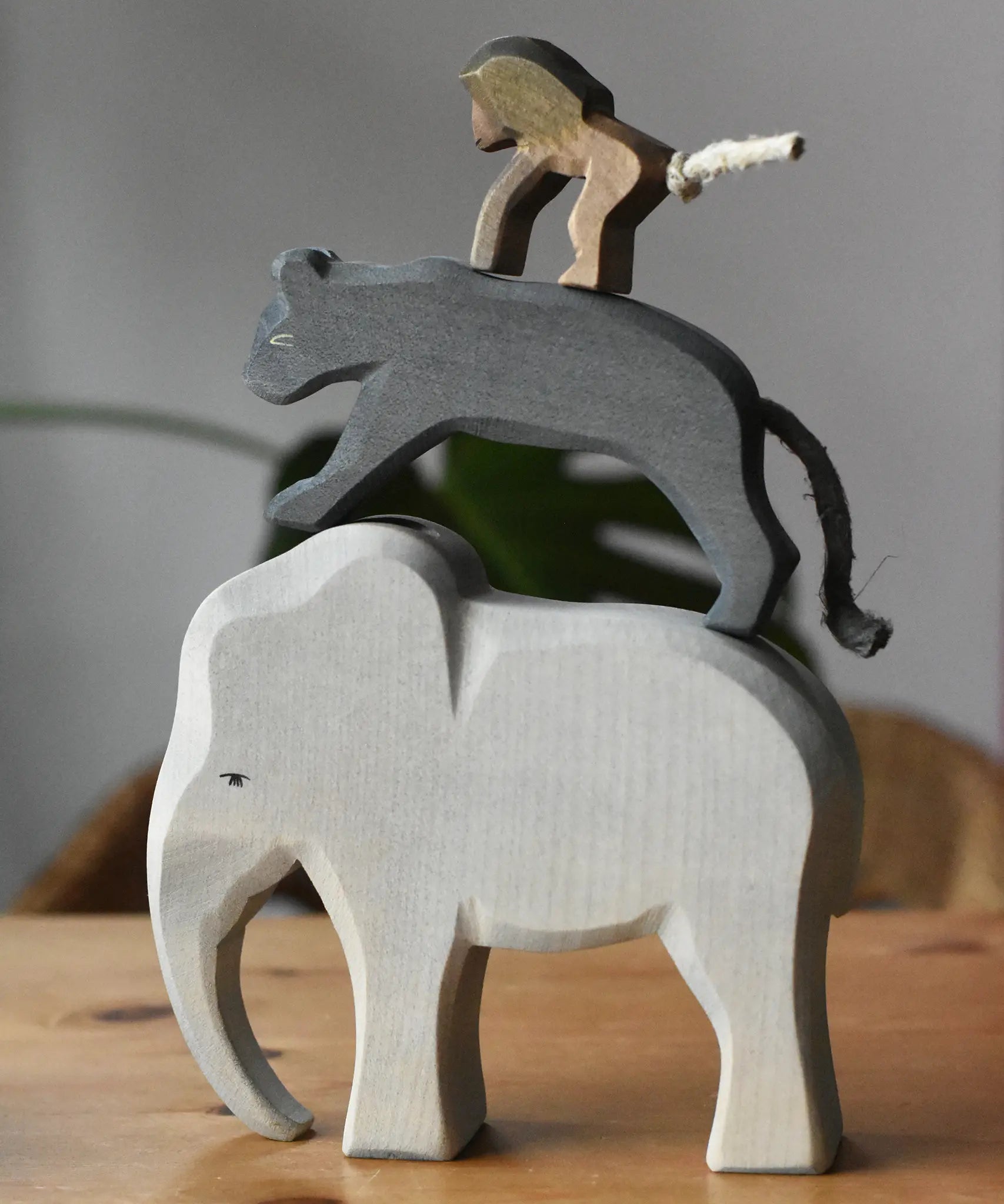 Stack of elephant, panther and baboon wooden toy figures on a wooden surface.  