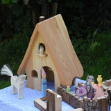 A collection of Ostheimer wooden toys placed around the fairy tales dolls house set up next to pieces of the Magic Wood castle. These wooden figures are part of a large range of expertly hand crafted, Waldorf inspired, wooden toys here at Babipur. 