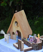 A collection of Ostheimer wooden toys placed around the fairy tales dolls house set up next to pieces of the Magic Wood castle. These wooden figures are part of a large range of expertly hand crafted, Waldorf inspired, wooden toys here at Babipur. 