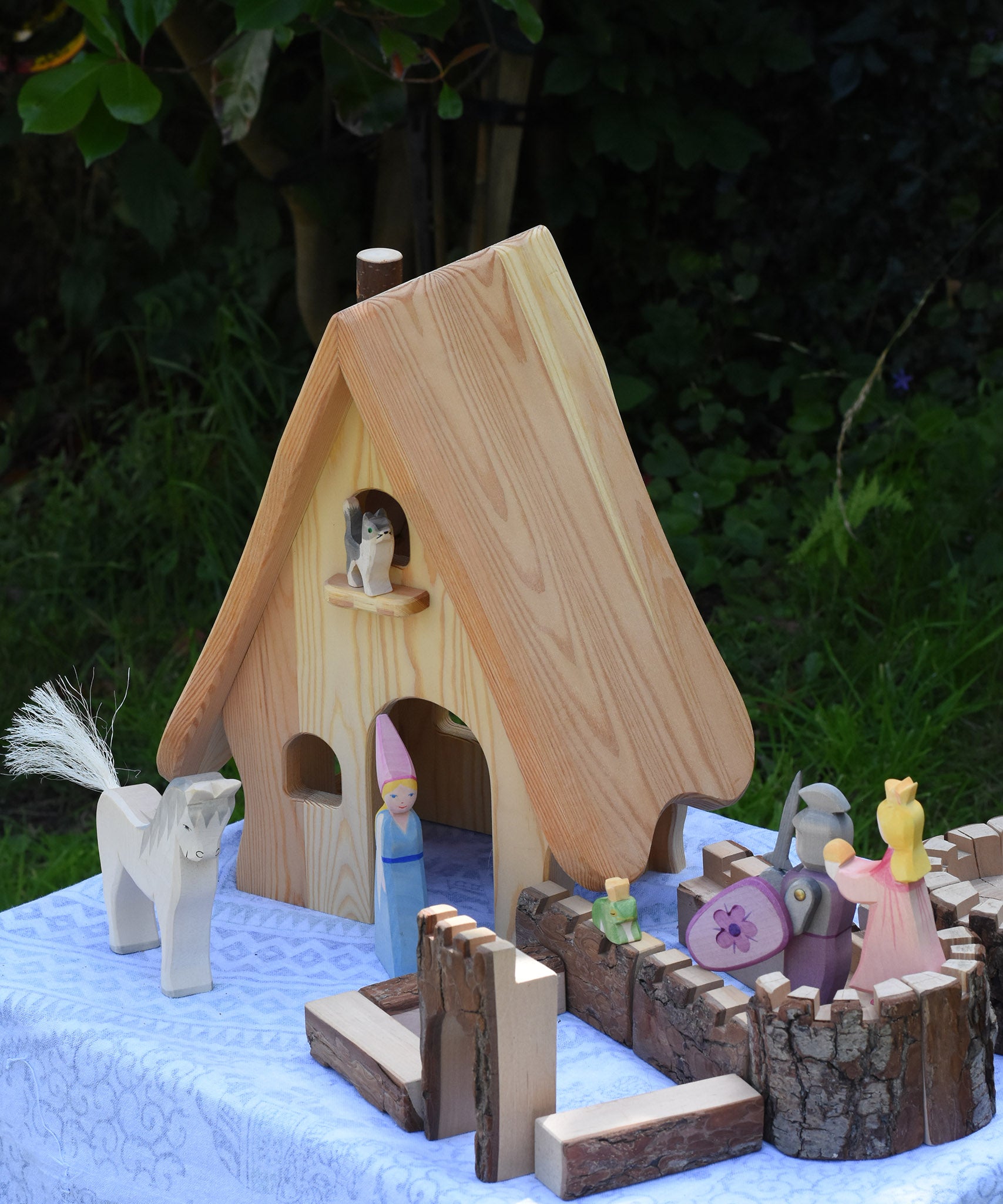 A collection of Ostheimer wooden toys placed around the fairy tales dolls house set up next to pieces of the Magic Wood castle. These wooden figures are part of a large range of expertly hand crafted, Waldorf inspired, wooden toys here at Babipur. 