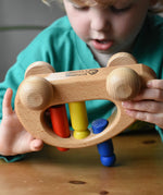 Ostheimer family van push along wooden toy with three people peg dolls. Child is tipping it upside down.
