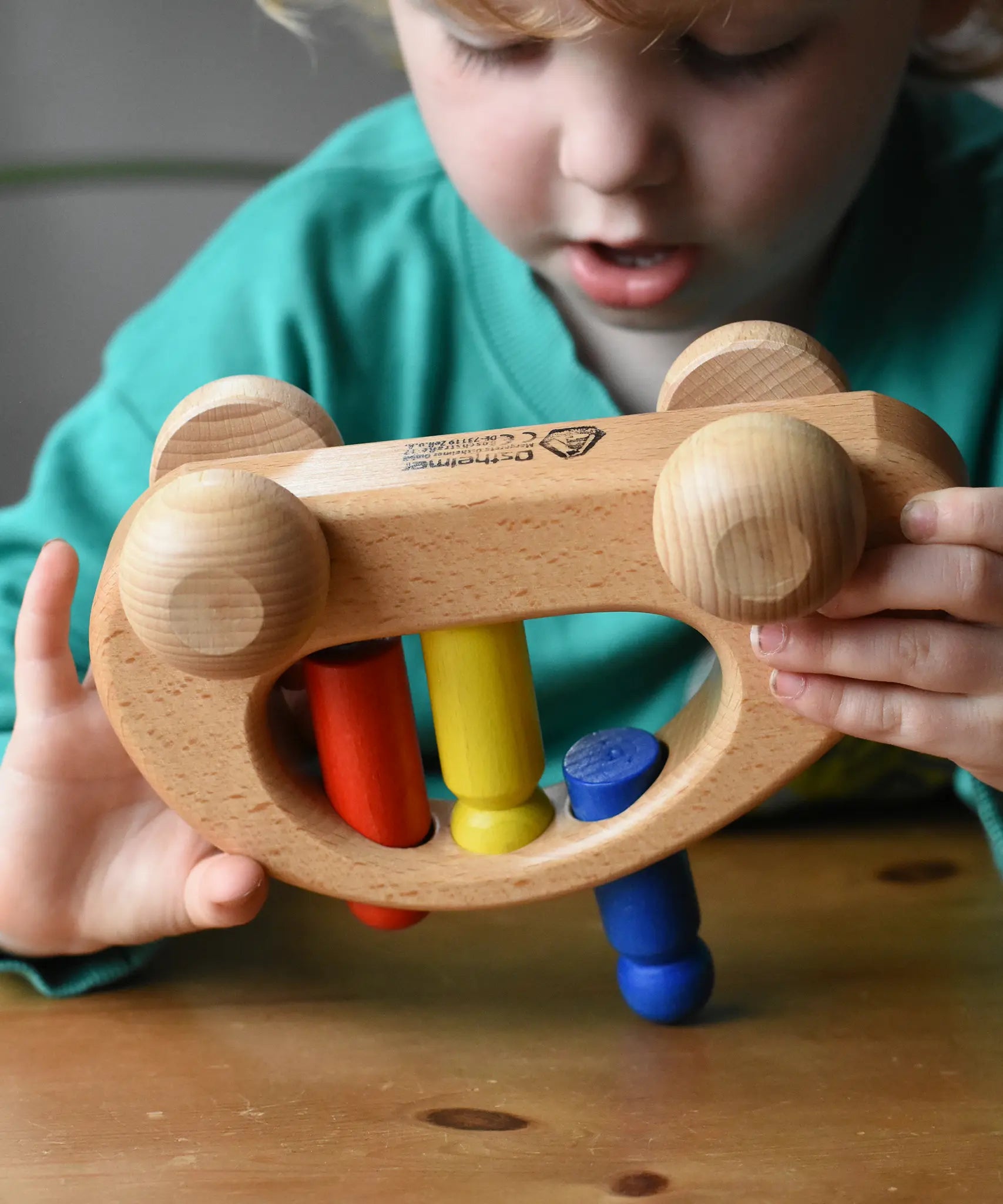 Ostheimer family van push along wooden toy with three people peg dolls. Child is tipping it upside down.