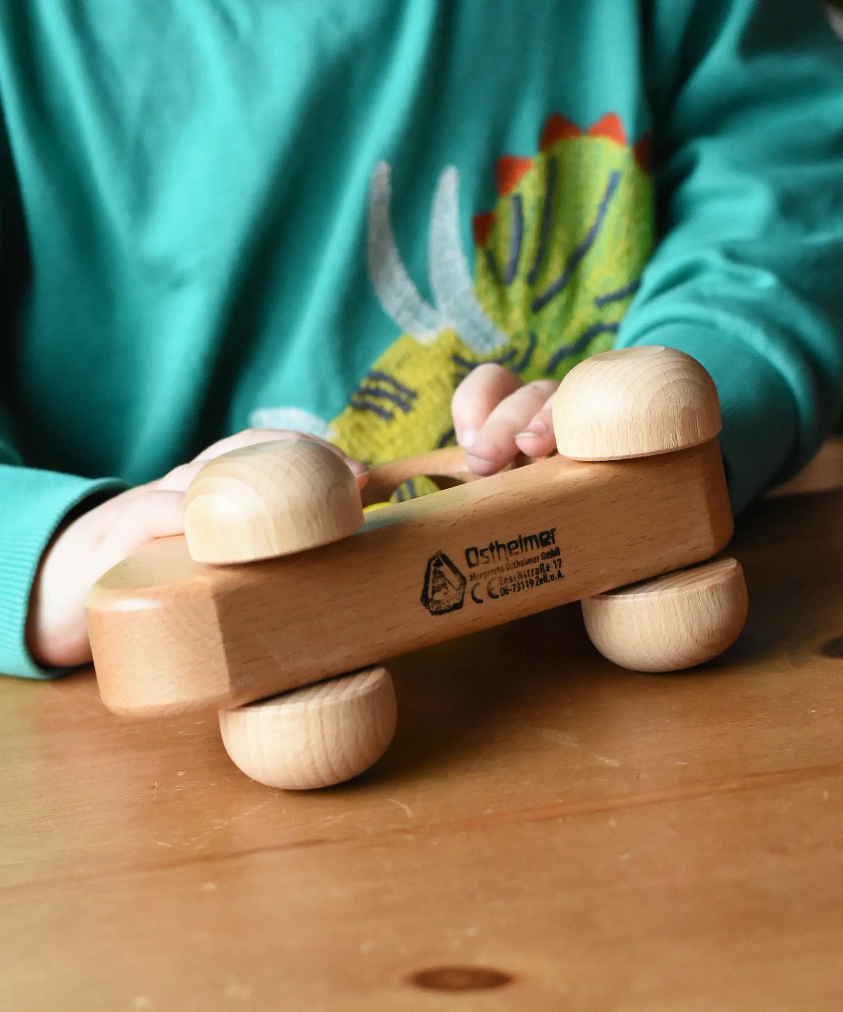 Close up of the logo on the bottom of the Ostheimer family van push along wooden toy with three people peg dolls. 