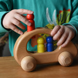 Child placing the red peg doll into the slot on the Ostheimer family van push along wooden toy.