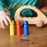 Ostheimer family van push along wooden toy with three people peg dolls lined up in front of it.