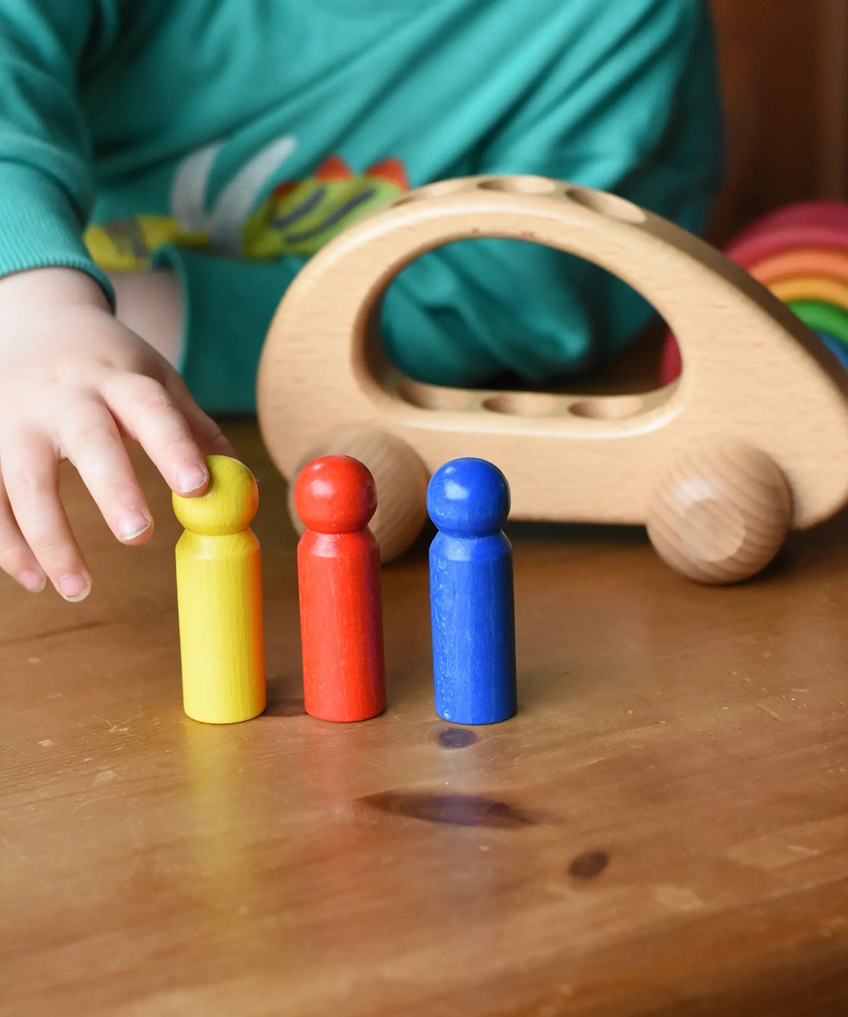Ostheimer family van push along wooden toy with three people peg dolls lined up in front of it.