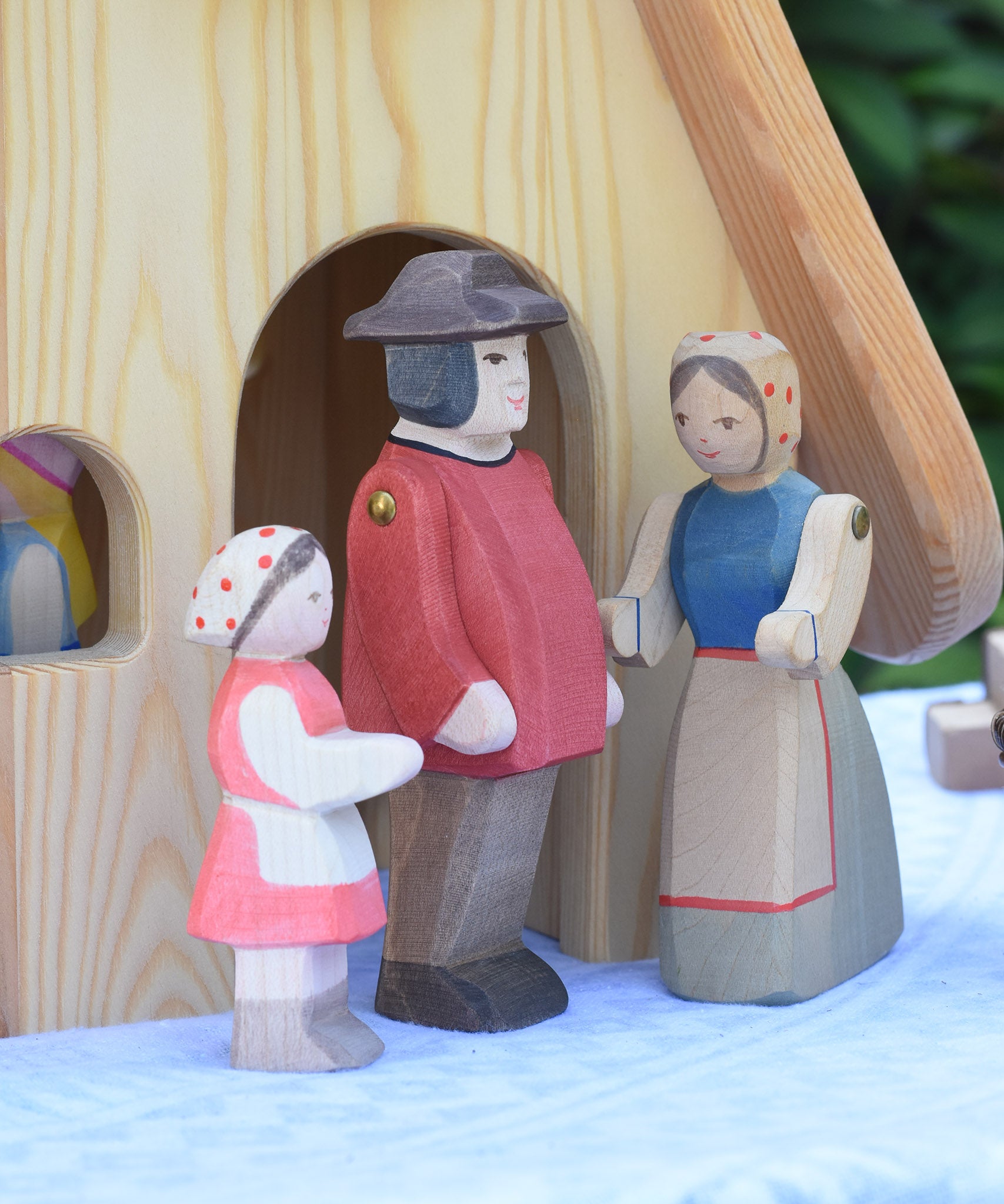 Ostheimer Heidi and male and female farmer figures placed in front of the Fairy Tale cottage. These wooden figures are part of a large range of expertly hand crafted, Waldorf inspired, wooden toys here at Babipur.