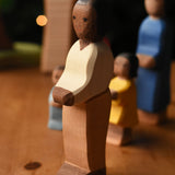An Ostheimer father wooden toy figure with brown skin placed at the front of a small world play scene. These wooden figures are part of a wide range of expertly hand crafted wooden toys here at Babipur.