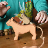 Ostheimer sitting baboon wooden toy figure placed on a female lioness figure. Child's hand reaching or the tail.
