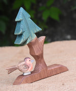An Ostheimer robin placed on teh base of on an Ostheimer fir tree.