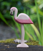 An Ostheimer flamingo bird placed on a mossy surface outdoors, blades of grass can be seen blurred in the background. This expertly hand crafted wooden figure is part of a large range of wooden toys here at Babipur.