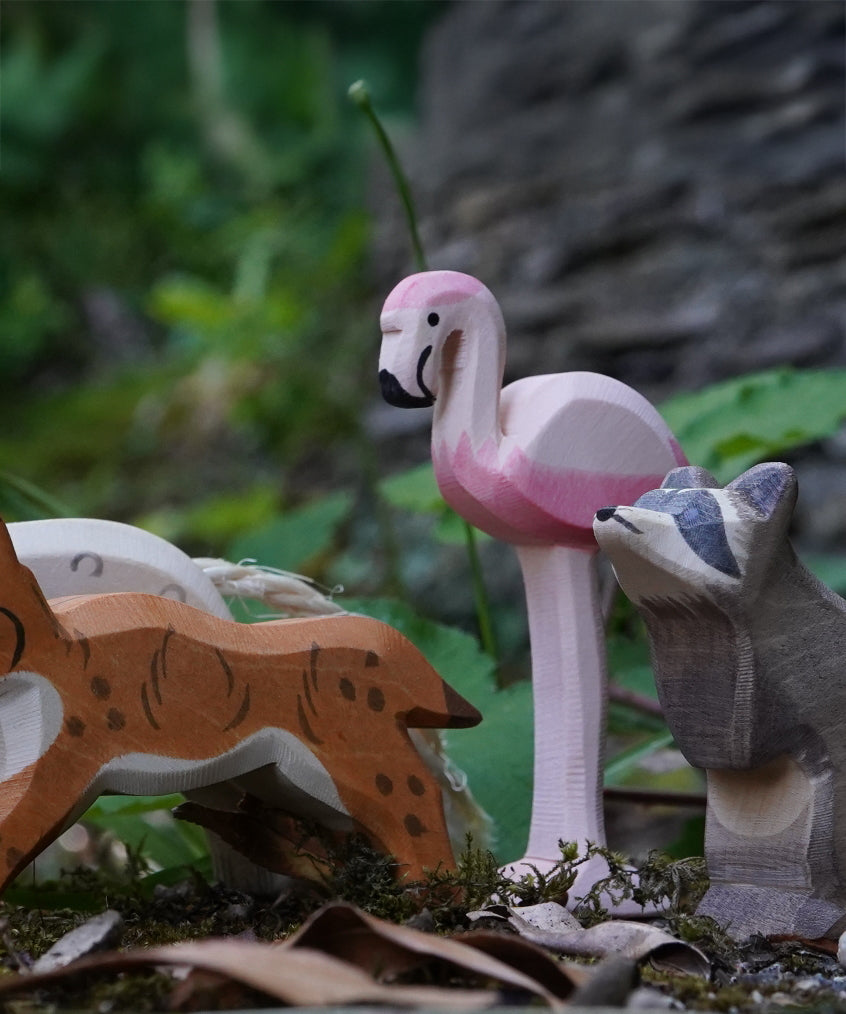Ostheimer wooden flamingo bird figure placed on a mossy surface outdoors. This expertly hand crafted wooden figure is part of a large range of wooden toys here at Babipur.