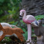 Ostheimer wooden flamingo bird figure placed on a mossy surface outdoors. This expertly hand crafted wooden figure is part of a large range of wooden toys here at Babipur.