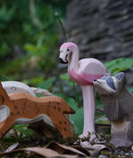 Ostheimer wooden flamingo bird figure placed on a mossy surface outdoors. This expertly hand crafted wooden figure is part of a large range of wooden toys here at Babipur.