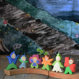 A collection of 6 Ostheimer wooden flower child figures placed on a natural Grimm's celebration ring. The six flower child figures include the gentian, forget-me-not, pansy, calendula, snowdrop and poppy.