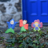 Three Ostheimer hand made and hand painted wooden Flower Children figures placed on a stone wall outdoors. The flower child figures include a gentian, poppy and pansy flower.
These flower child wooden figures are part of a wide range of expertly hand crafted wooden toys here at Babipur. 