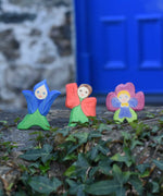 Three Ostheimer hand made and hand painted wooden Flower Children figures placed on a stone wall outdoors. The flower child figures include a gentian, poppy and pansy flower.
These flower child wooden figures are part of a wide range of expertly hand crafted wooden toys here at Babipur. 