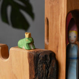 Ostheimer frog king wooden toy figure placed on a castle wall with a medieval princess in a tower in the background. 