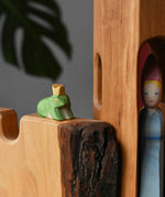 Ostheimer frog king wooden toy figure placed on a castle wall with a medieval princess in a tower in the background. 