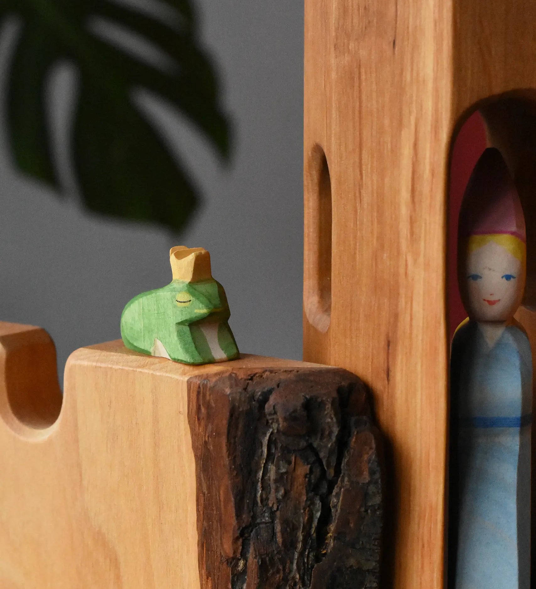 Ostheimer frog king wooden toy figure placed on a castle wall with a medieval princess in a tower in the background. 