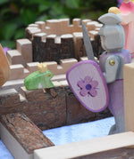 An Ostheimer fog prince wooden toy figure placed on the walls of a Magic Wood castle. The Ostheimer pink knight is standing to one side.  These wooden figures are part of a large range of expertly hand crafted wooden toys here at Babipur. 