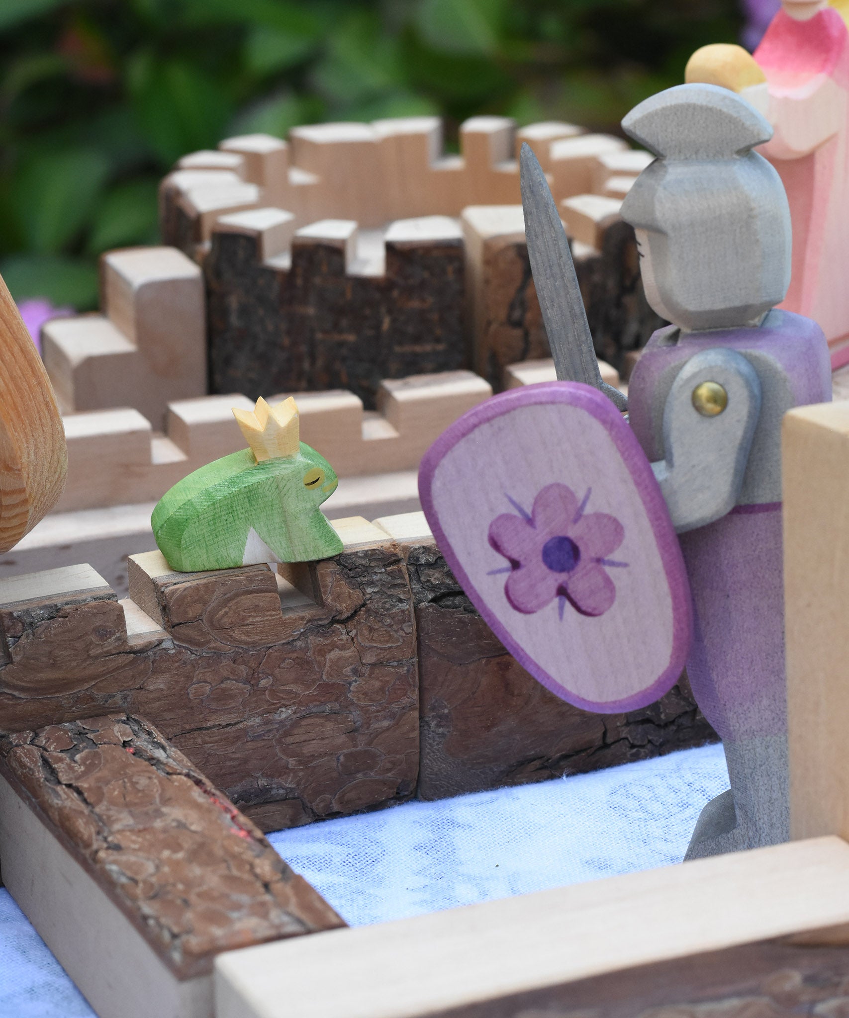 An Ostheimer fog prince wooden toy figure placed on the walls of a Magic Wood castle. The Ostheimer pink knight is standing to one side.  These wooden figures are part of a large range of expertly hand crafted wooden toys here at Babipur. 