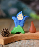 An Ostheimer hand made and hand painted wooden Gentian Flower Child figure toy placed on a natural Grimm's celebration ring. These flower child wooden figures are part of a wide range of expertly hand crafted wooden toys here at Babipur. 