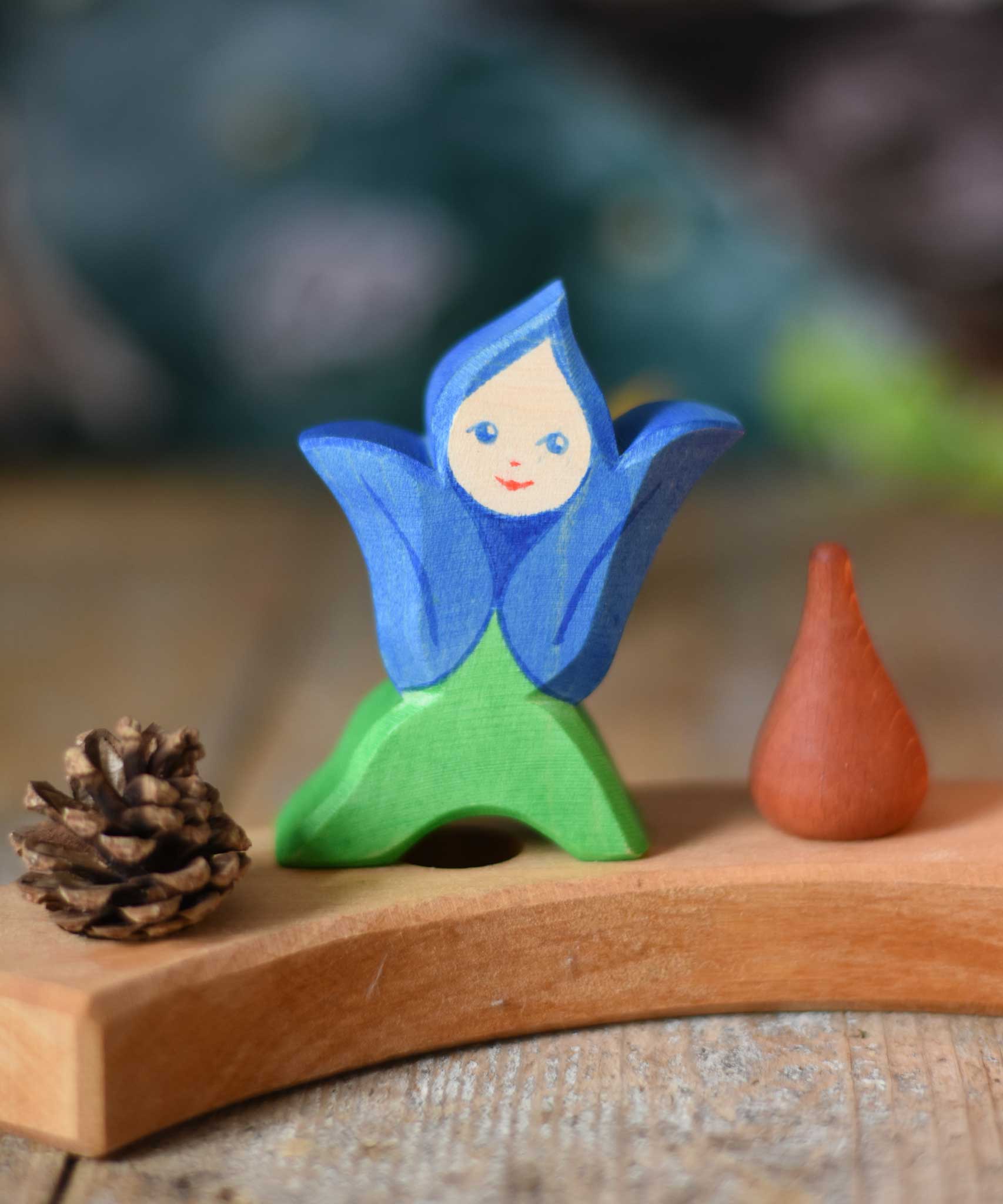 An Ostheimer hand made and hand painted wooden Gentian Flower Child figure toy placed on a natural Grimm's celebration ring. These flower child wooden figures are part of a wide range of expertly hand crafted wooden toys here at Babipur. 
