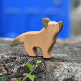 Ostheimer German shepherd wooden toy figure placed on a stone wall outdoors. 