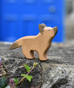Ostheimer German shepherd wooden toy figure placed on a stone wall outdoors. 