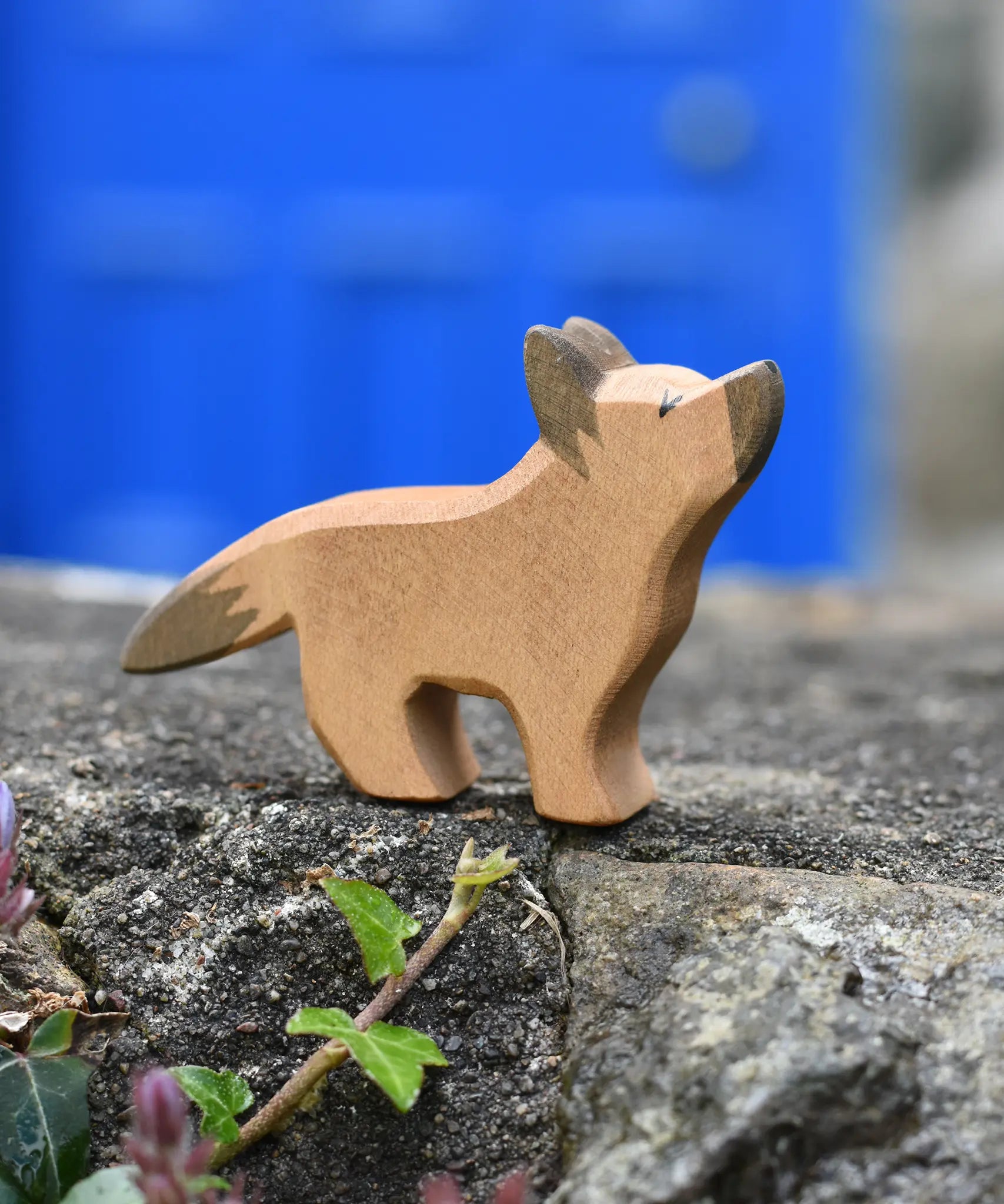 Ostheimer German shepherd wooden toy figure placed on a stone wall outdoors. 